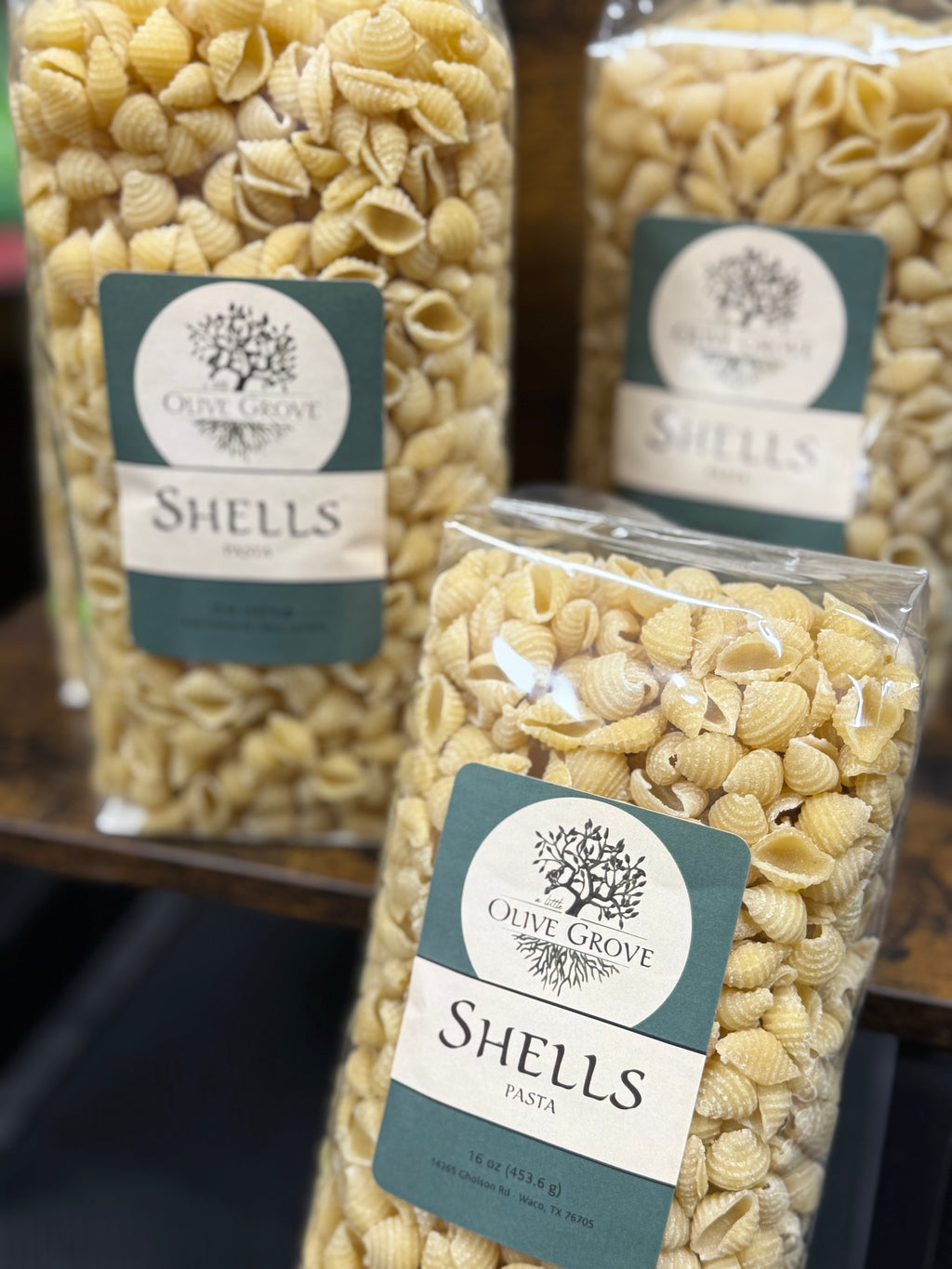 Packages of Olive Grove Shells pasta with labels on a blurred background