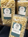 Packages of Olive Grove Shells pasta with labels on a blurred background